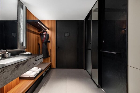 Une salle de bain moderne avec un lavabo en marbre, un meuble-lavabo en bois et une porte noire.
