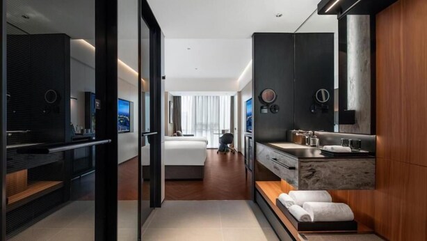 A modern hotel room with a large bed, a sitting area, a bathroom with a vanity, and a large mirror. - IntercityHotel Shanghai Hongqiao NECC (Shanghai)