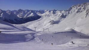 Un paysage de montagne enneigé, avec des pistes de ski et un ciel dégagé.
