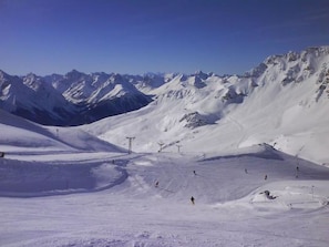 A snow-covered mountain landscape with ski slopes and a clear sky. - Chasa Mundin ****, (Scuol). by Interhome (Scuol)