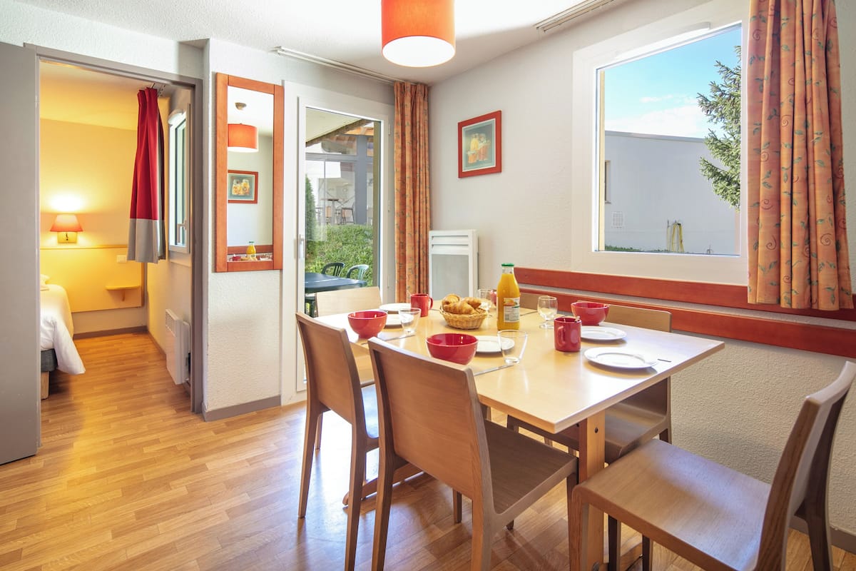 A dining area with a wooden table, chairs, and a window with curtains.
