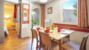 A dining area with a wooden table, chairs, and a window with curtains.