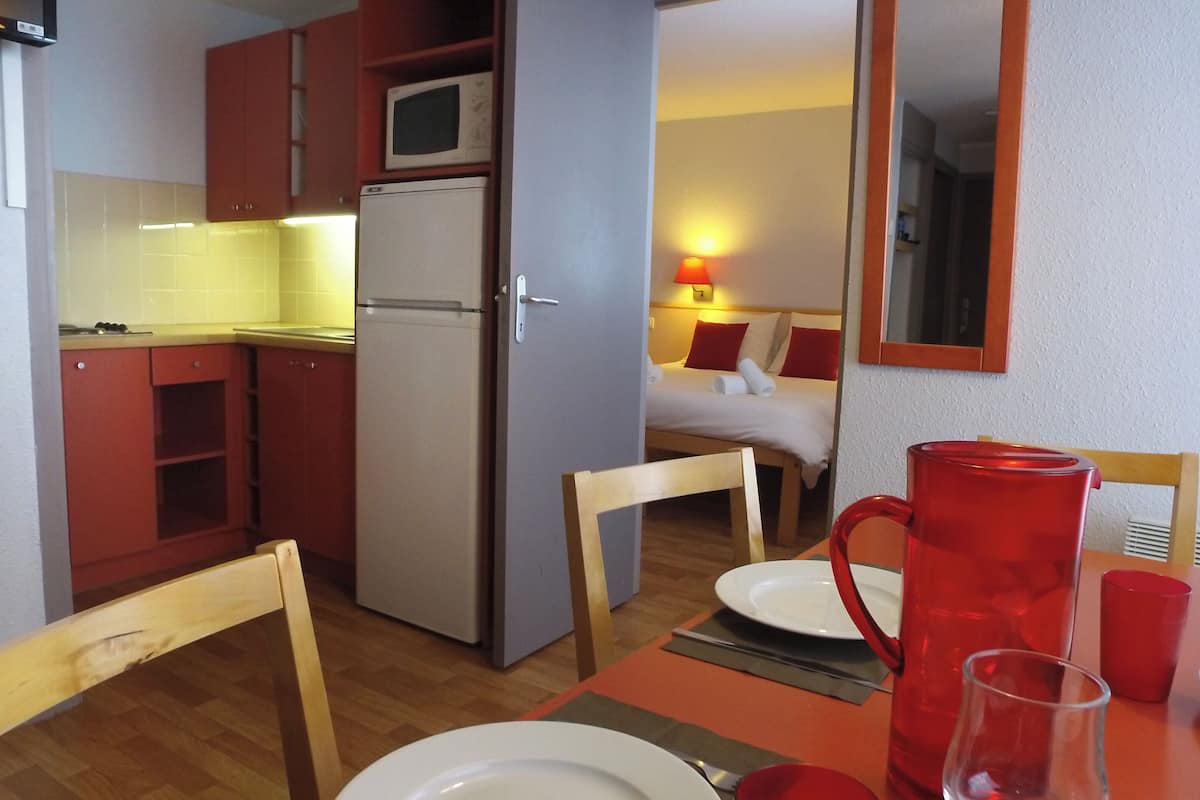 A compact kitchen with a microwave, refrigerator, and wooden cabinets.
