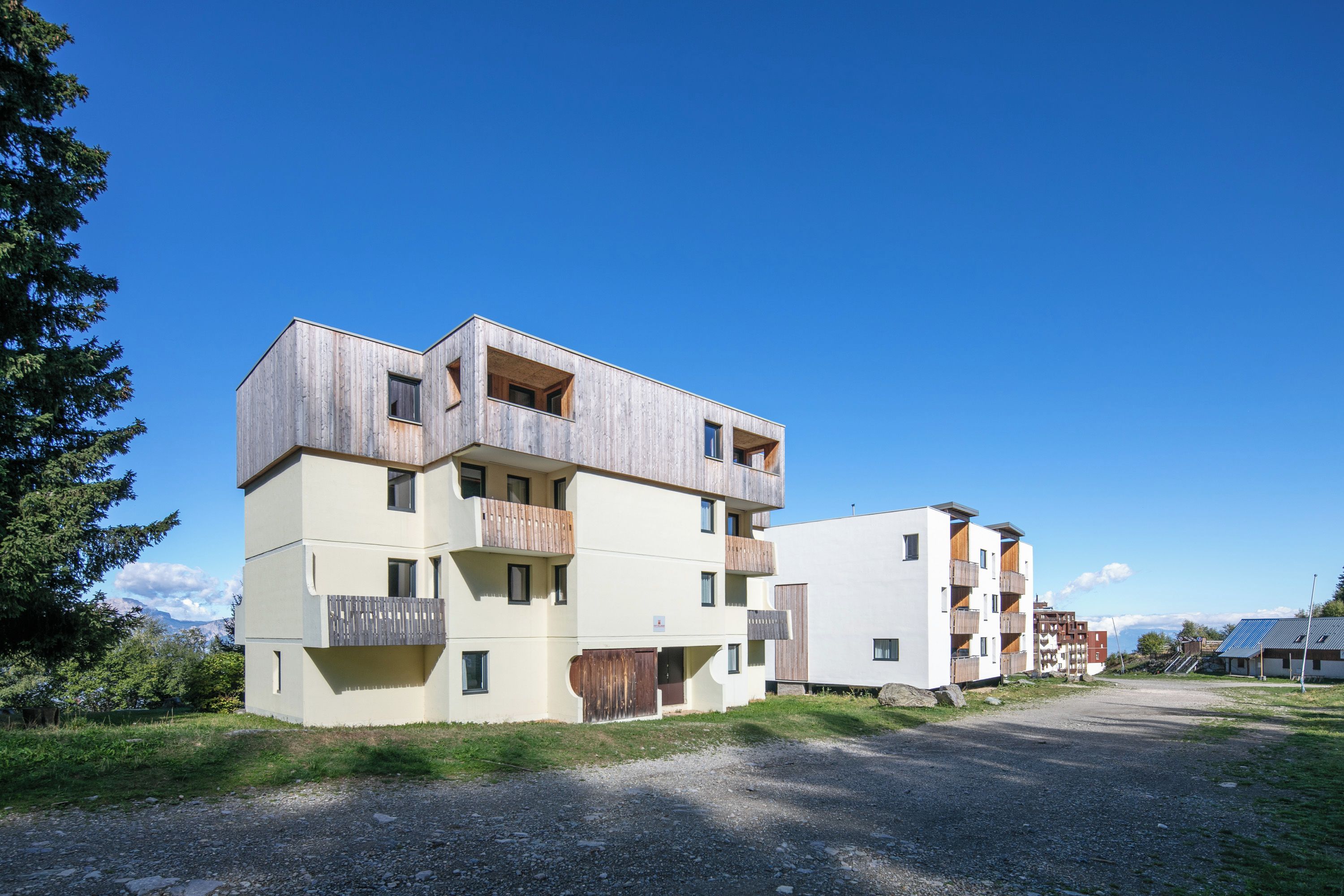 Un edificio residencial moderno de varios pisos con balcones y un camino de entrada de grava.