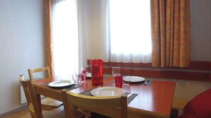 A dining table with chairs, plates, cutlery, and a red mug. - Vvf Villages Prapoutel (Les Adrets)