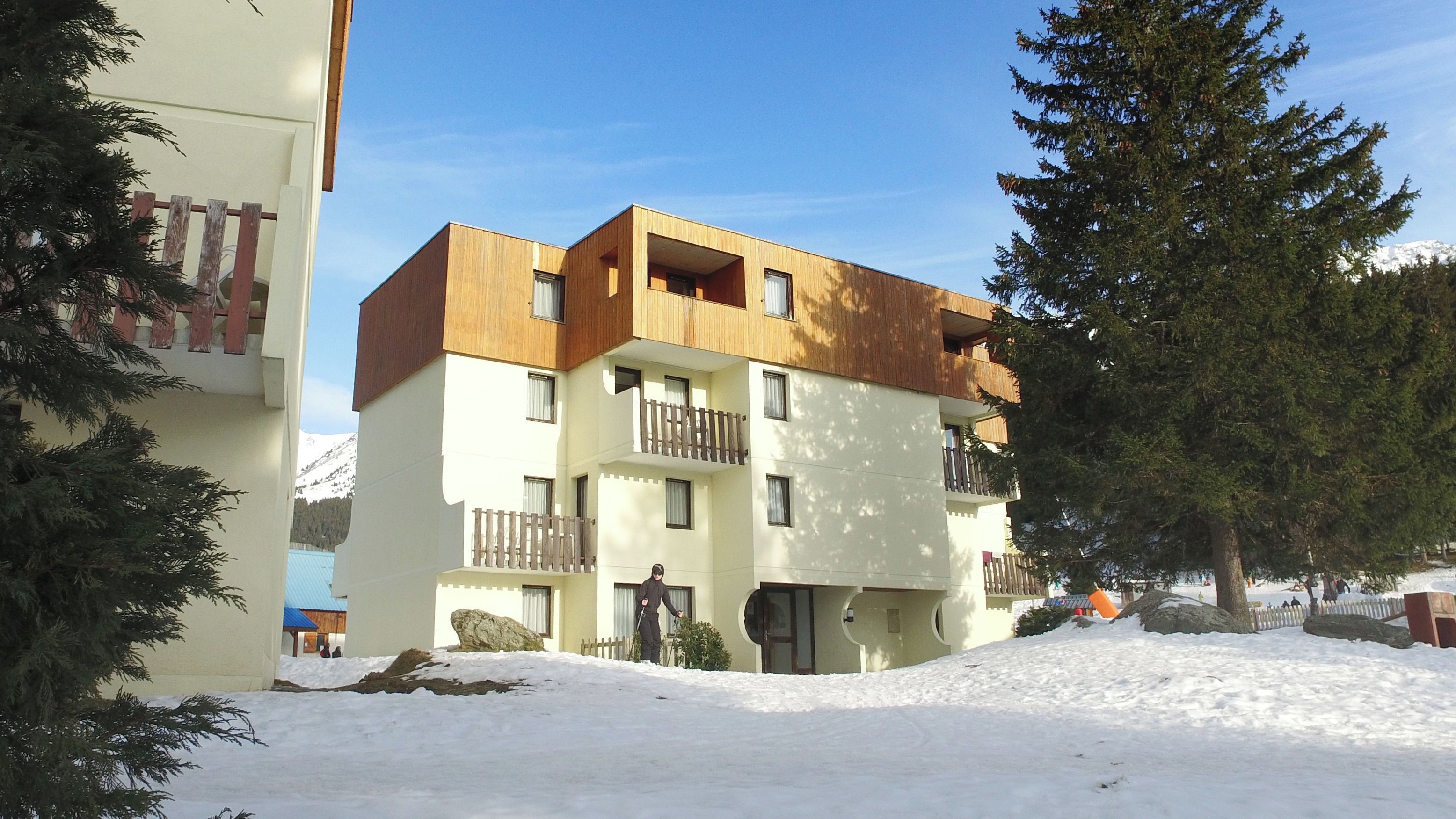 A multi-story building with balconies and a snow-covered ground.