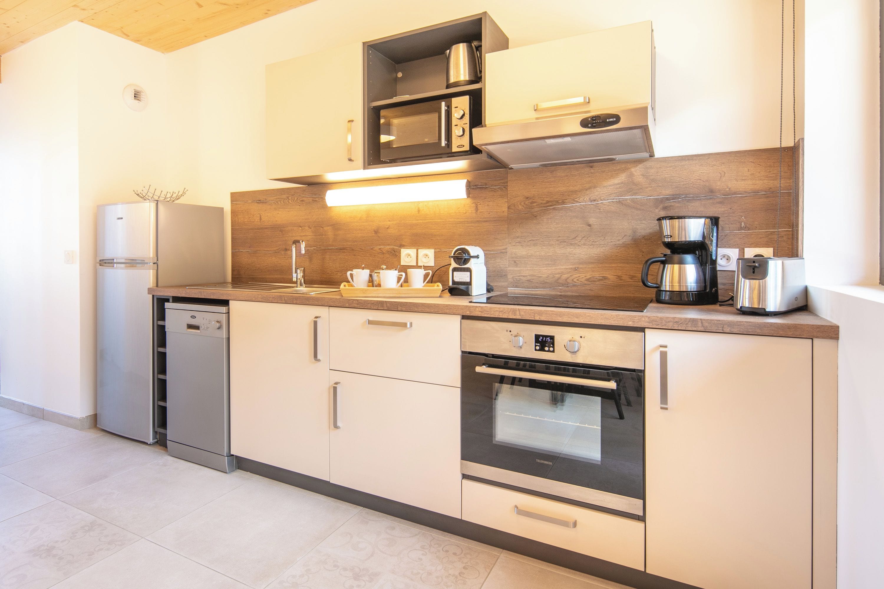 Una cocina moderna con electrodomésticos de acero inoxidable, protector contra salpicaduras de madera y horno empotrado.
