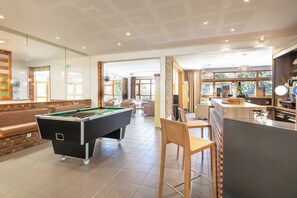 A pool table in a well-lit room with a bar area and seating. - Vvf Villages Prapoutel (Les Adrets)