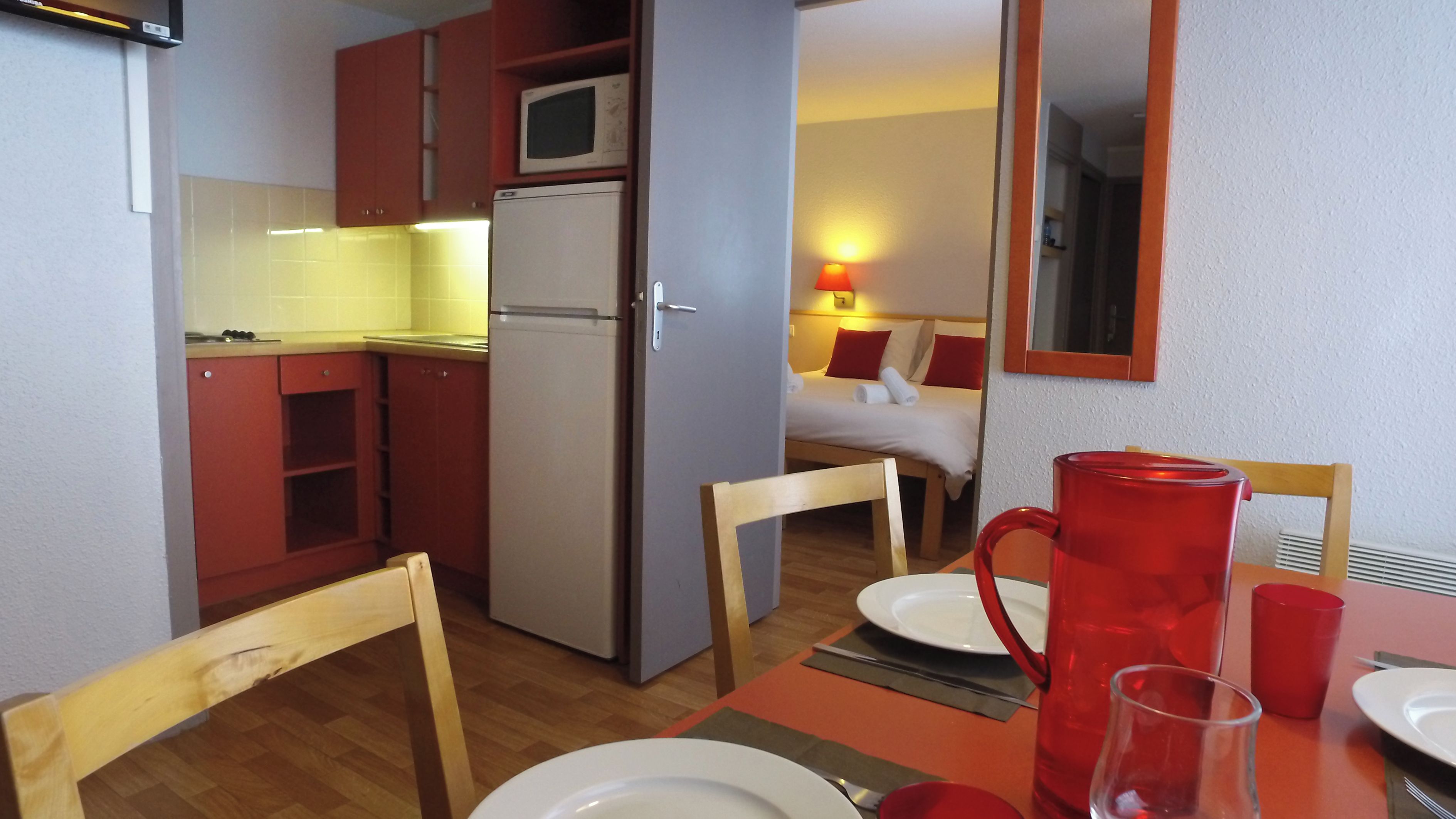 Una cocina compacta con microondas, refrigerador y armarios de madera.