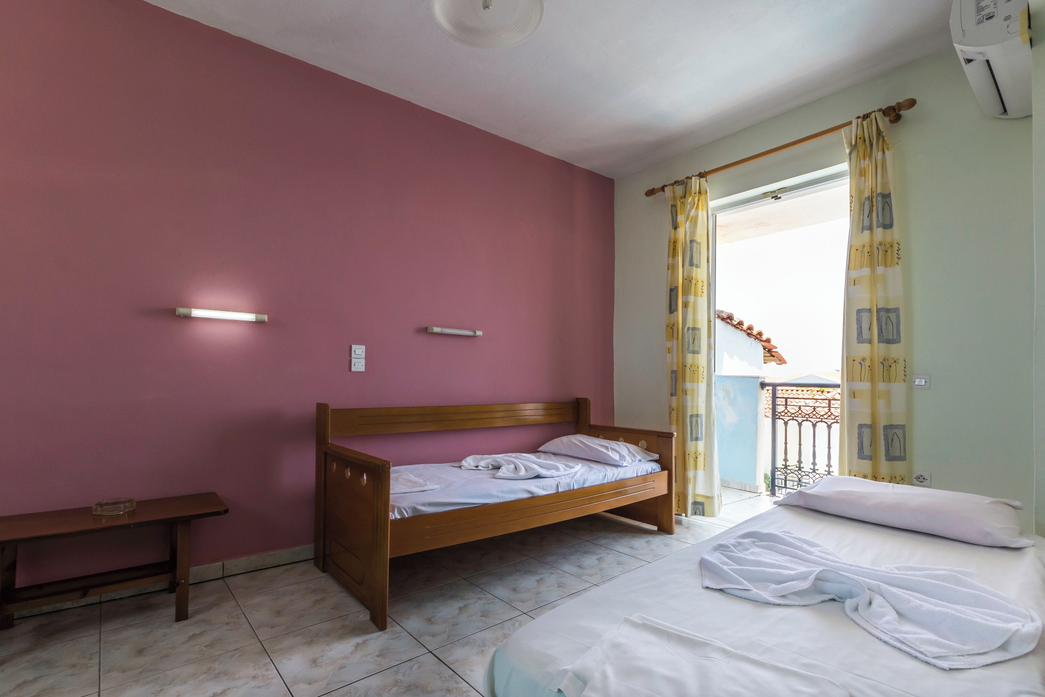 A bedroom with a single bed, a wooden bench, and a small table.