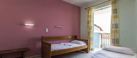 A bedroom with a single bed, a wooden bench, and a small table.