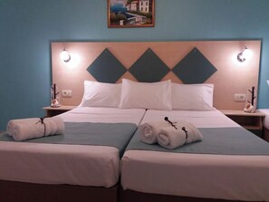 A double bed with two pillows, a headboard with diamond patterns, bedside tables with lamps, and a painting on the wall. - Vossos (Zakynthos)