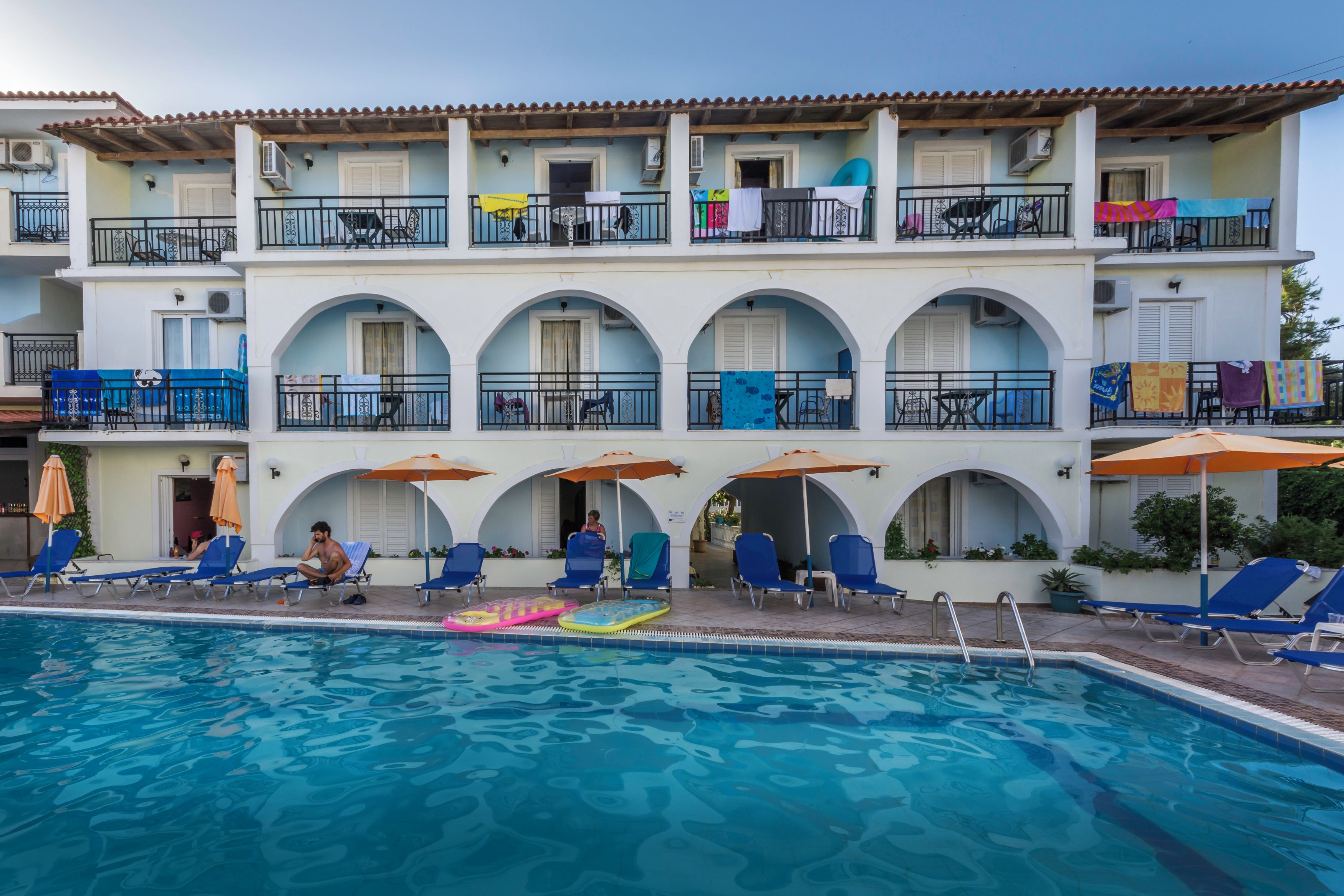 Un hotel con piscina, numerosi balconi e aree salotto all'aperto.
