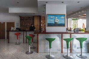 A bar area with a bartender, a ship painting, and a view of the outdoors. - Vossos (Zakynthos)