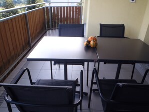 A balcony with a table and chairs, a wooden fence, and a view of trees. - Via da Liuns 790, (Scuol) by Interhome (Scuol)