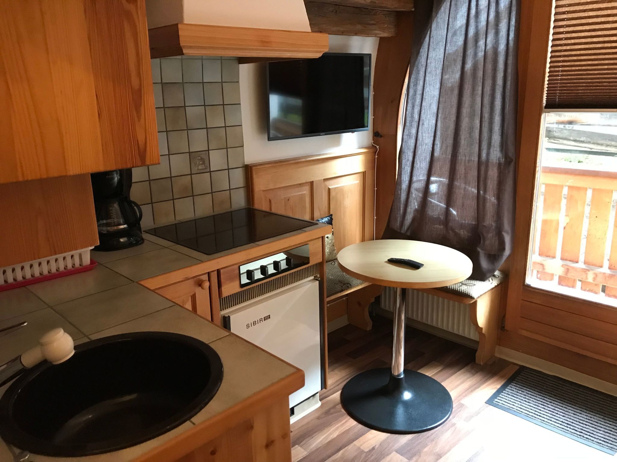 Ett kompakt kök med diskmaskin, diskho och ett litet matbord.