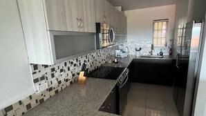 Une cuisine moderne avec des meubles en bois clair, un dosseret carrelé en noir et blanc, un plan de travail en granit et un four encastré.