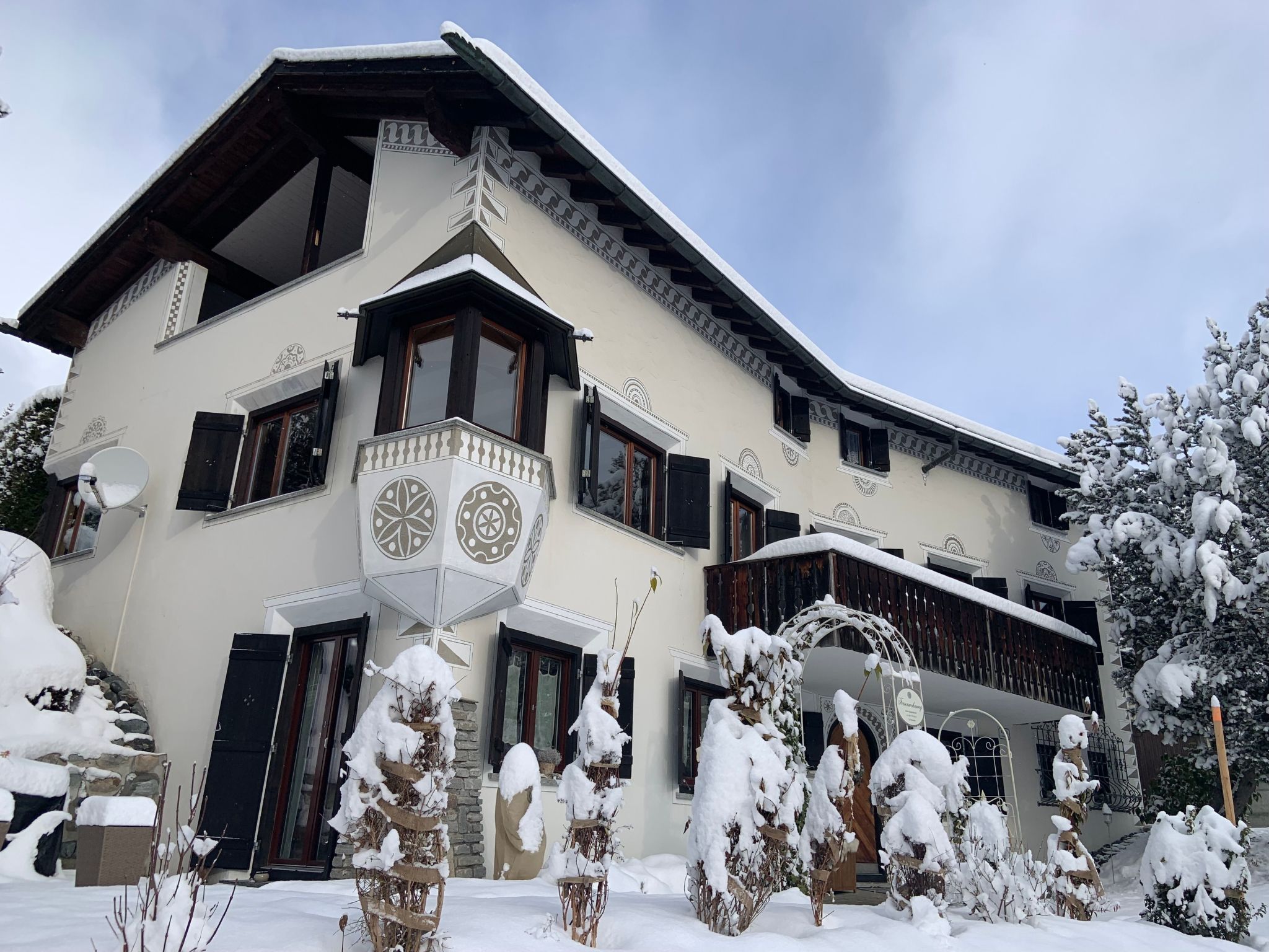 Un immeuble à plusieurs étages doté d’un balcon, des arbres couverts de neige et un ciel dégagé.