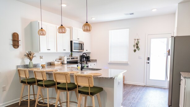 A kitchen with white cabinets, a central island with bar stools, a microwave, and a refrigerator. - 3-bedroom house in fabulous Summerton next to lake (Summerton)
