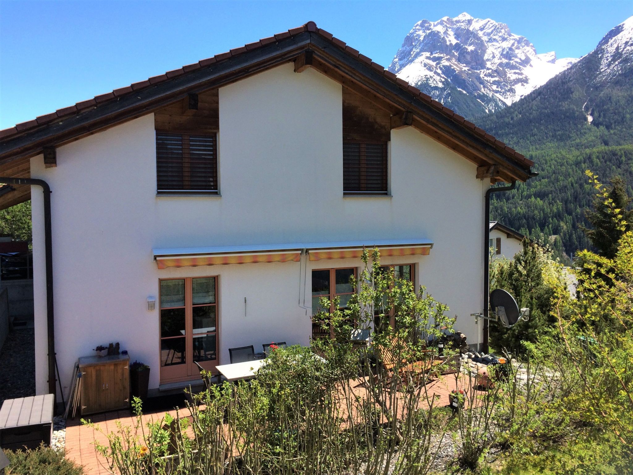 A two-story house with a balcony, a satellite dish, and a mountain view in the background.