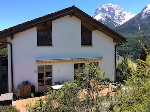 Une maison à deux étages avec un balcon, une antenne parabolique et une vue sur les montagnes en arrière-plan.