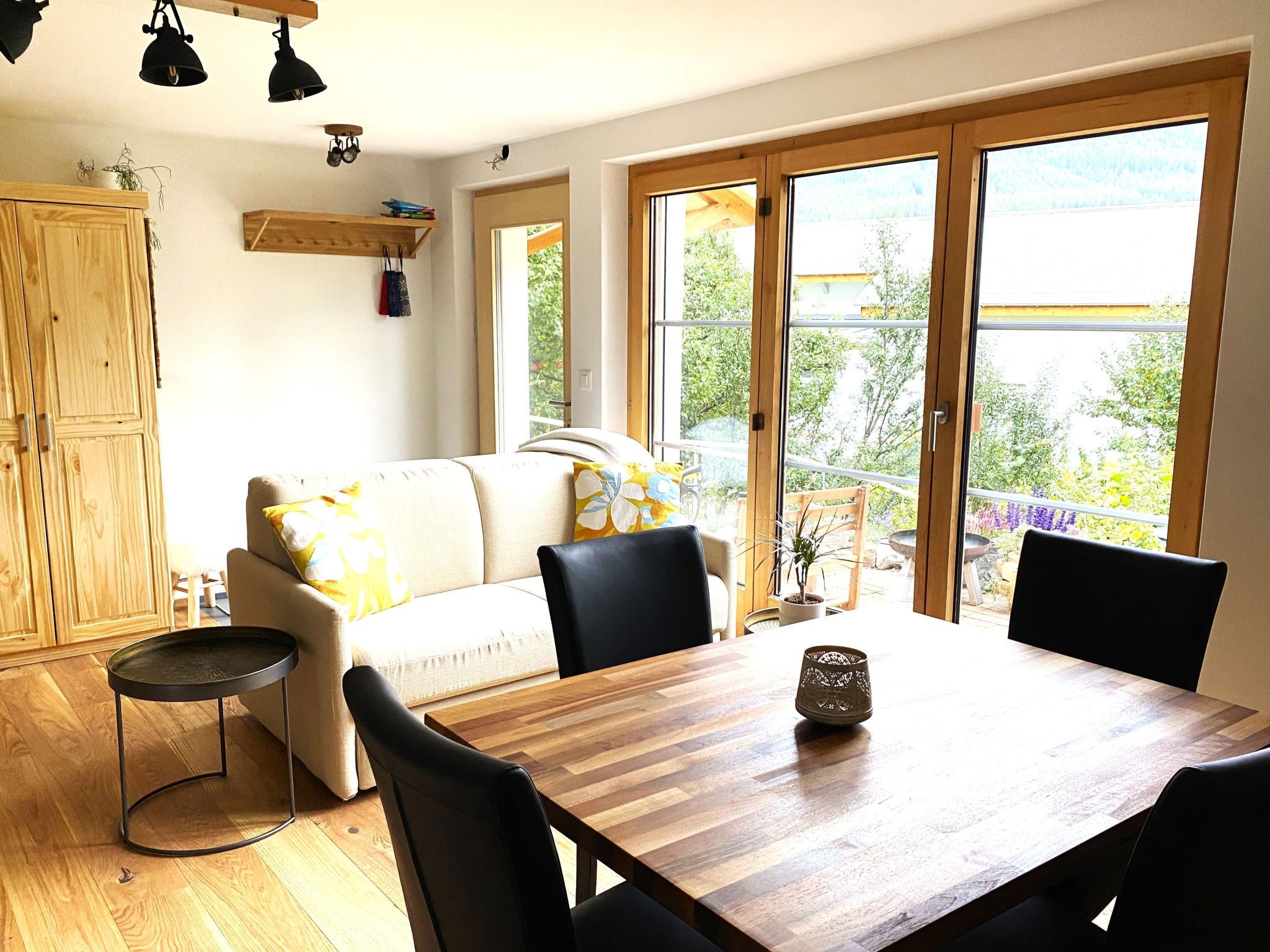 Un área de estar acogedora con un sofá, una mesa de comedor y sillas. Hay un aparador de madera y una pequeña mesa redonda.