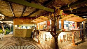 Een bar met een houten vloer, een toonbank met een bord waarop 'TOURS' staat, en een constructie in de vorm van een boom.