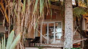 Een houten gebouw met een veranda, een hangmat en een palmboom.
