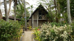 Un bungalow doté d’un escalier menant à l’entrée, entouré d’une végétation tropicale.