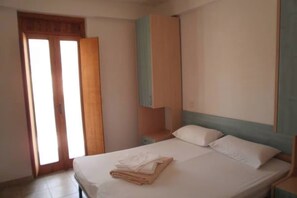 Un dormitorio con cama, mesita de noche, armario y puerta.