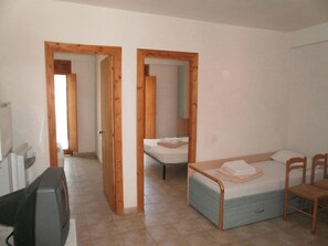 Una habitación con cama, escritorio y silla. Hay puertas de madera que dan a otra habitación.