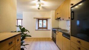 Eine Küche mit Holzausstattung, einem schwarzen Kühlschrank und einem Fenster mit Blick.
