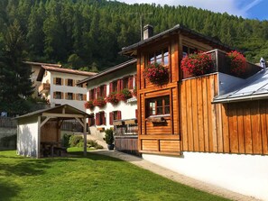 A wooden building with balconies, a covered area, and a mountainous backdrop.