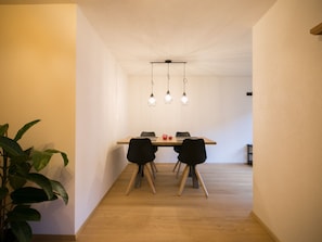 A dining area with a wooden table, black chairs, and pendant lighting.