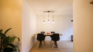 Ein Essbereich mit einem Holztisch, schwarzen Stühlen und Pendelleuchten.