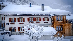 Ein Hotel mit verschneitem Dach, roten Fensterläden und Holzbauweise.