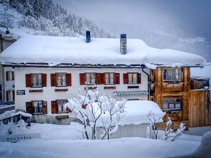 A hotel with a snow-covered roof, red shutters, and a wooden structure. - Chasa Allegra, (Müstair) by Interhome (Müstair)