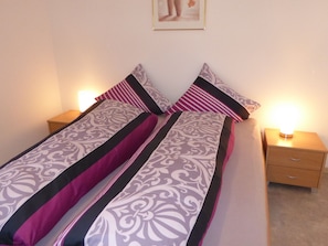 Un lit avec une literie à motifs, deux tables de chevet avec des lampes et un tableau accroché au mur.