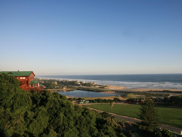 A coastal view with a wooden house, a beach, and a body of water.