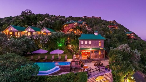 A hillside resort with multiple buildings, a swimming pool, and outdoor seating areas. - Under the Boardwalk Guest House (Wilderness)