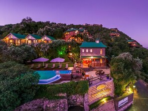 A hillside resort with multiple buildings, a swimming pool, and outdoor seating areas. - Under the Boardwalk Guest House (Wilderness)