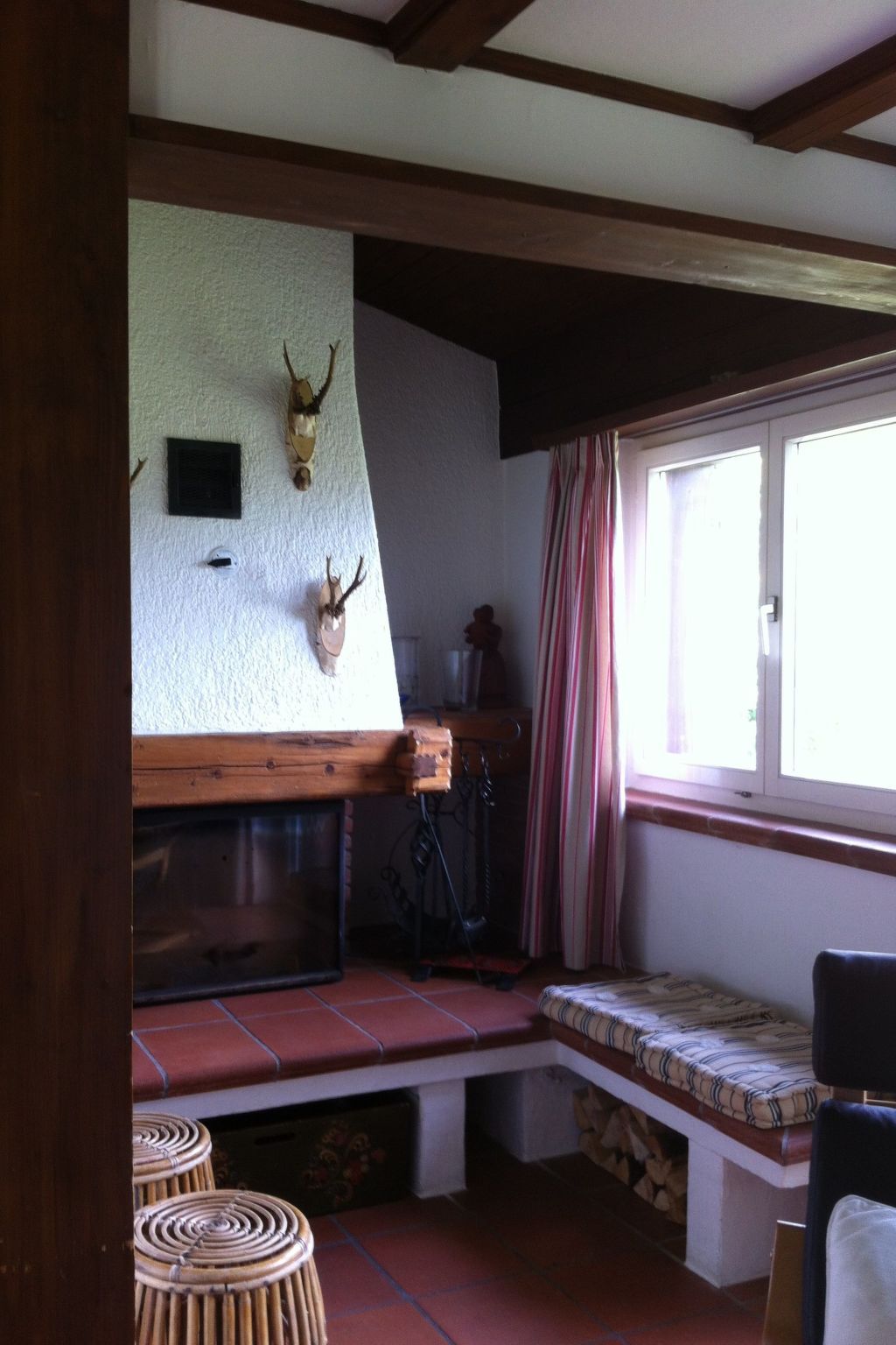 A rustic interior with a wooden bench, a fireplace, and wall-mounted antlers.