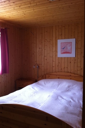 Une chambre rustique en bois, avec un lit, une petite table de chevet et un tableau accroché au mur.