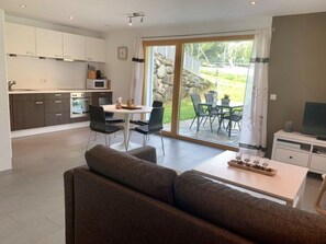 A modern kitchen with a dining area and a sofa. - Chasa Sumovia, (Sta. Maria - Santa Maria Val Müstair) by Interhome (Sta. Maria GR)