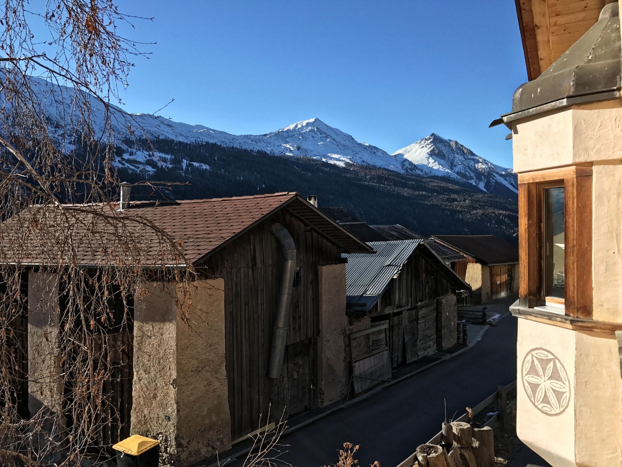 Ein malerisches Bergdorf mit Holzhäusern und einem schneebedeckten Berg im Hintergrund.