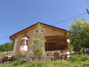 A two-story building with a balcony, a satellite dish, and a wooden fence. - Ferienhaus Chasa Silva, (Lüsai) by Interhome (Lü)