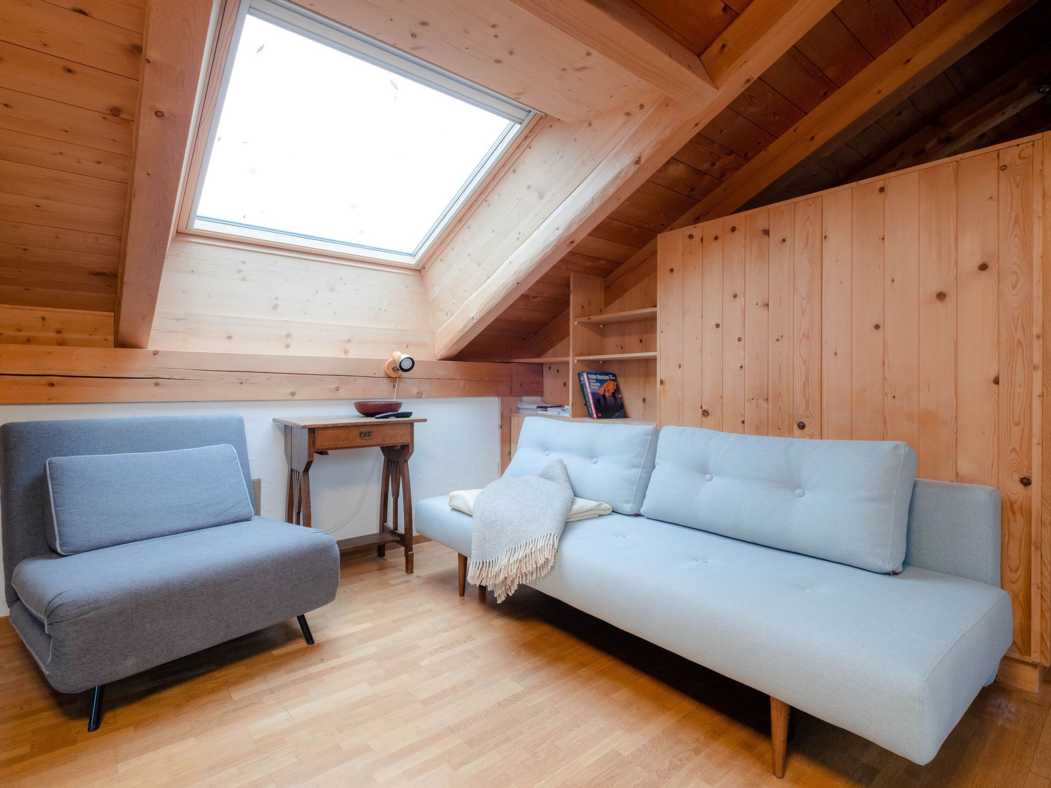 A cozy room with a loft bed, a sofa, and a small table.