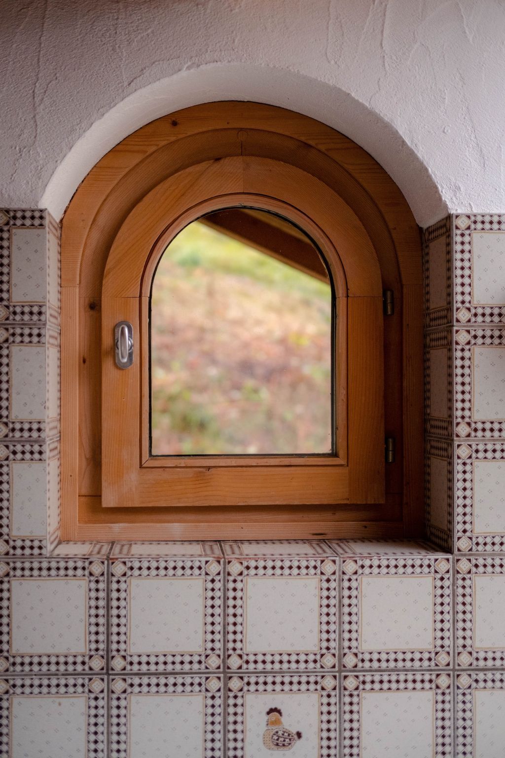 A window with an arched wooden frame and a view of a garden.
