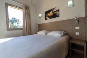 A hotel room with a large bed, a window with curtains, a wall-mounted painting, and bedside lamps. - Paese Serenu (Porto-Vecchio)