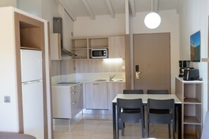 Una cocina moderna con electrodomésticos integrados, un comedor con mesa y sillas, y vistas al exterior.